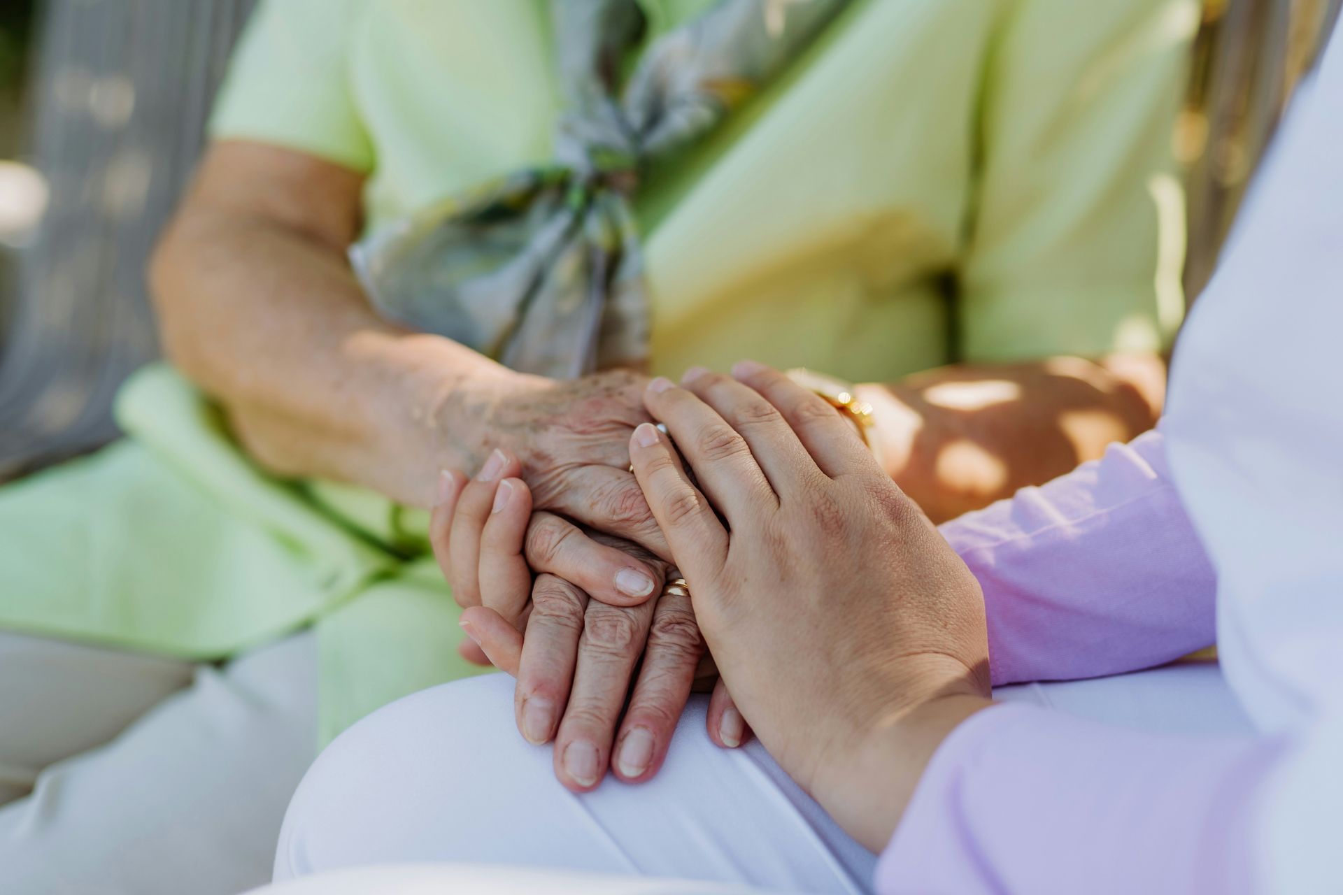 A nurse is holding the hands of an elderly woman.