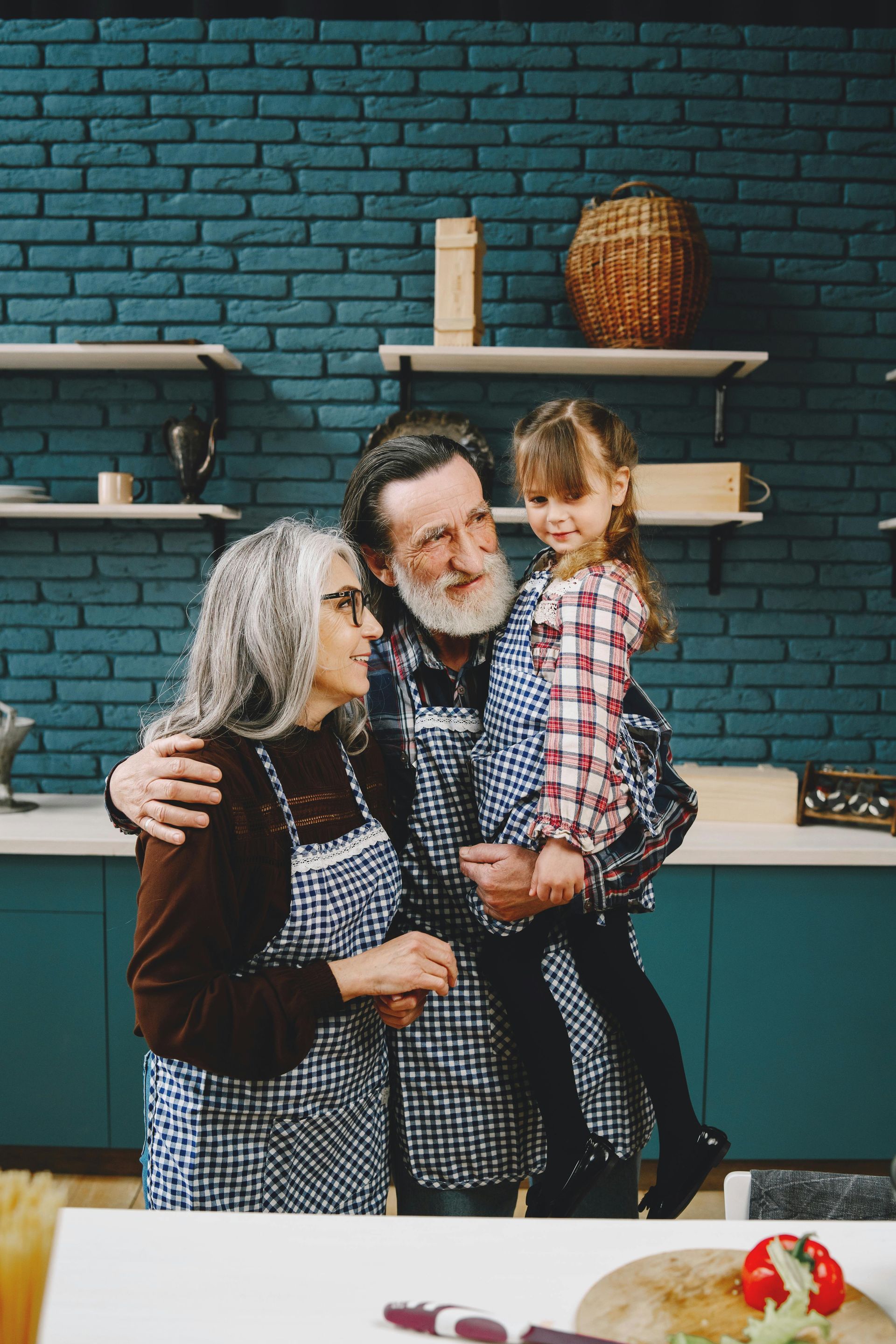 A man and woman are holding a little girl in a kitchen.