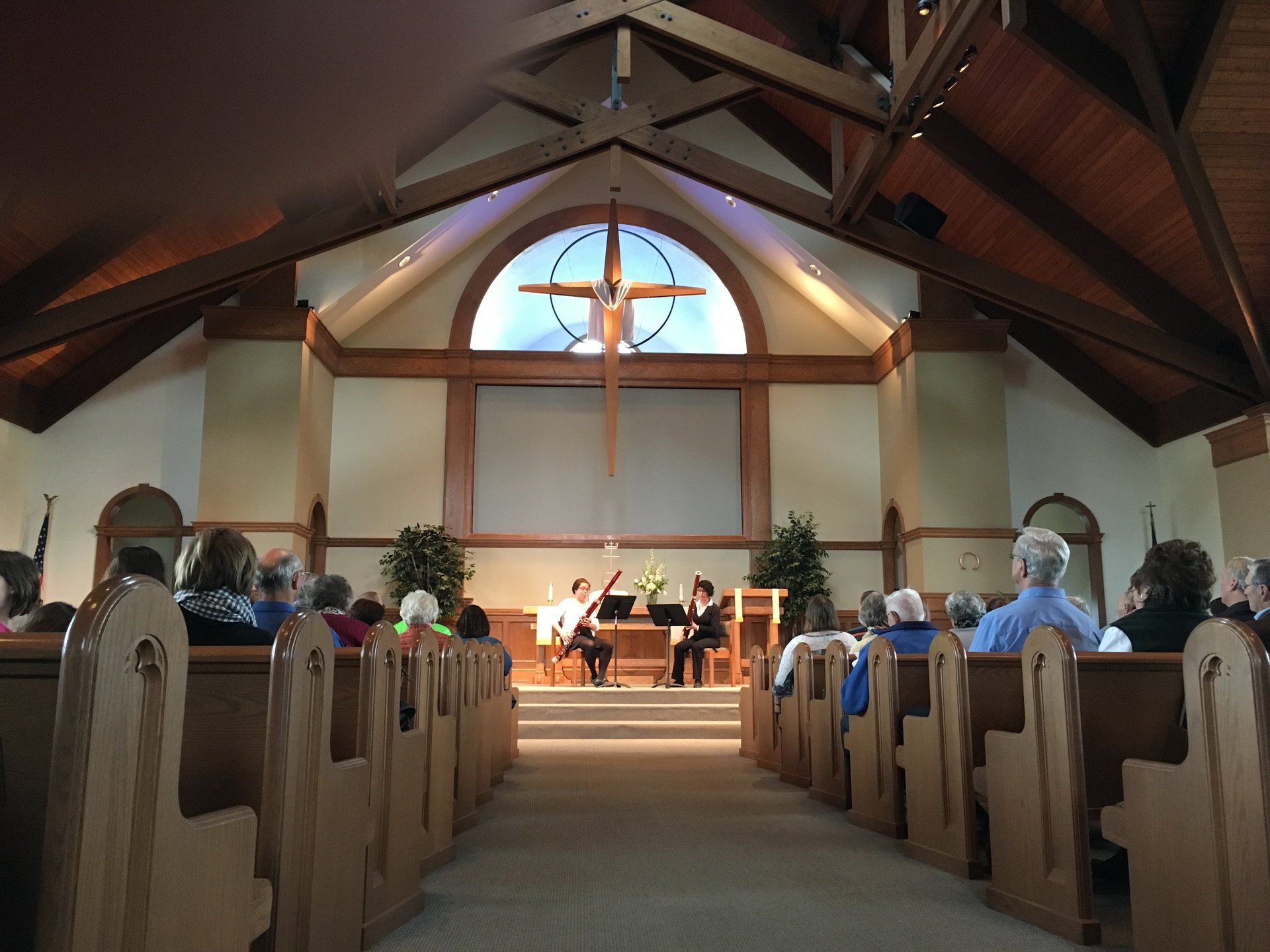 Interior church scene: musicians on stage, cross above, audience in pews.