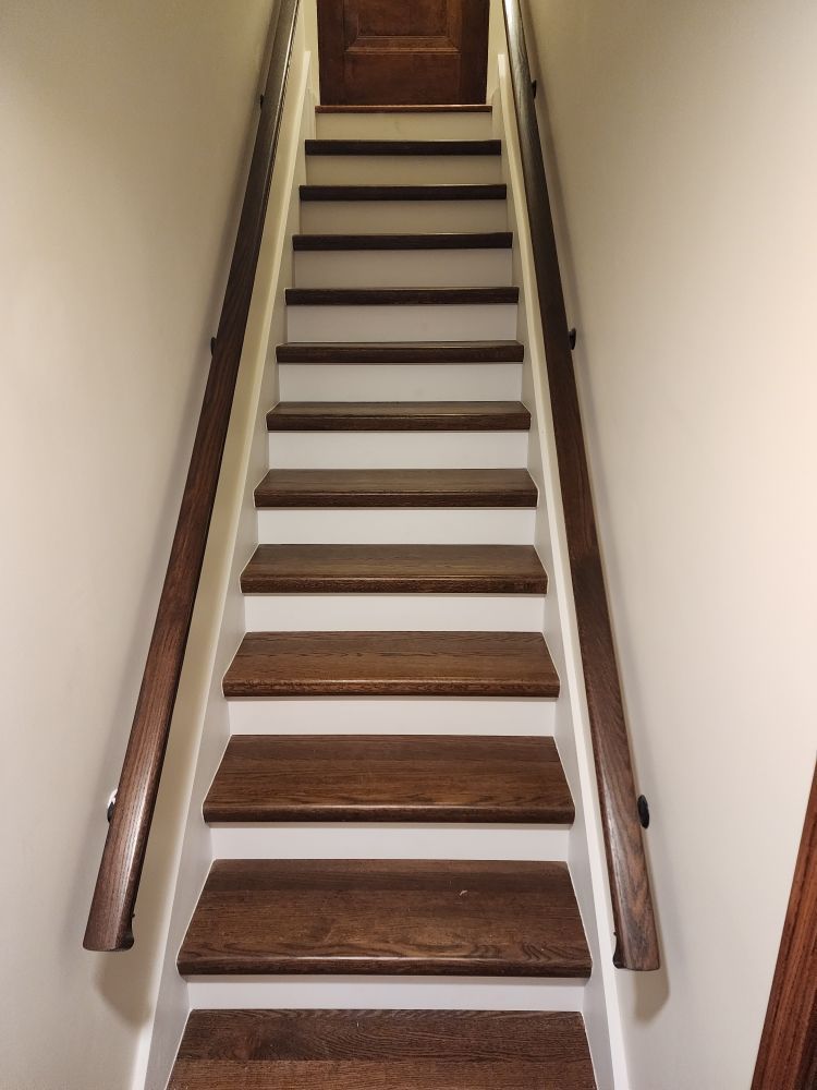 Wooden staircase with white risers and brown handrails.