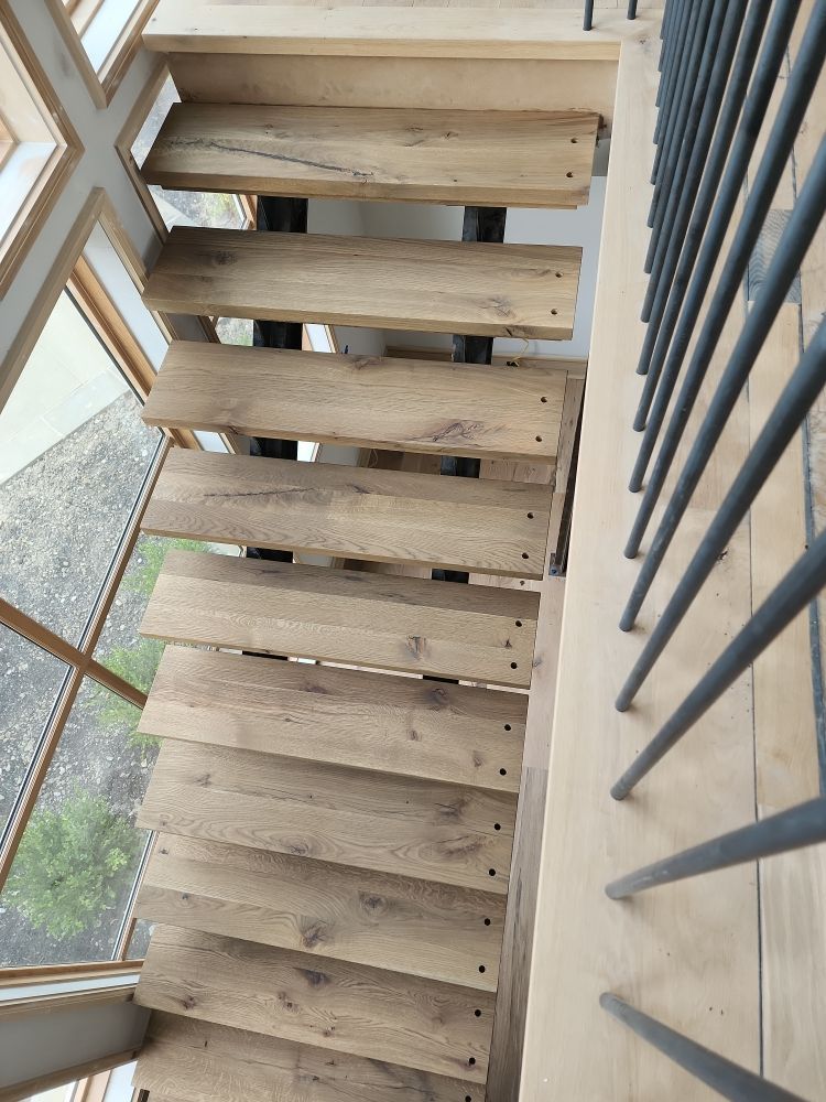 Wooden staircase with metal railing and window view.