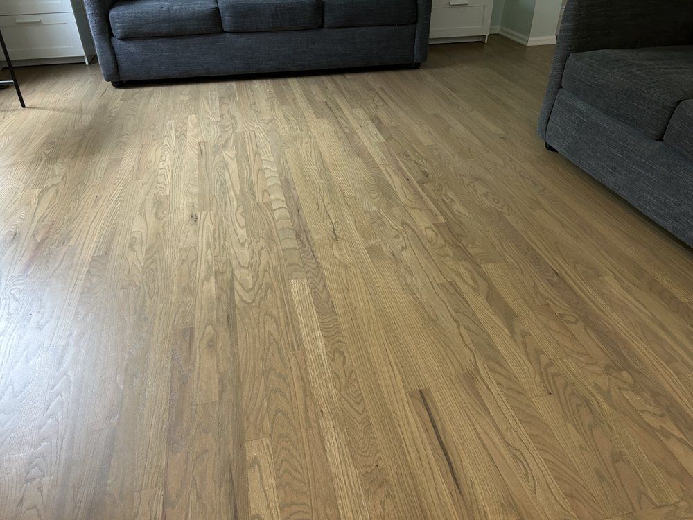 Wooden floor with two gray sofas in a living room setting.