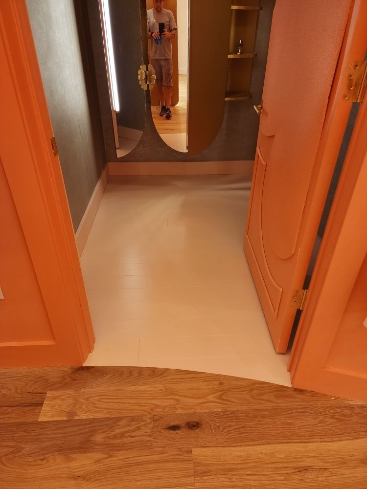 Orange doors open to a white-floored space. A mirror reflects a person.