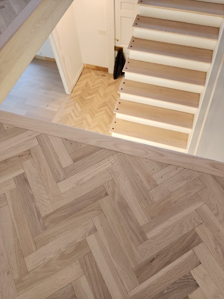 Herringbone wood floor, stairs and landing, light wood tones.