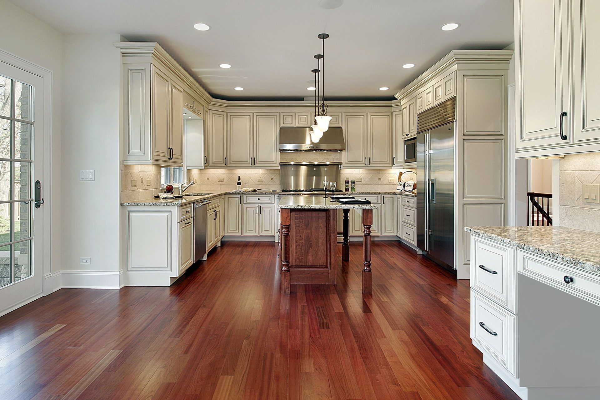 Spacious kitchen with wood floors, light cabinets, stainless steel appliances, and a dark island.