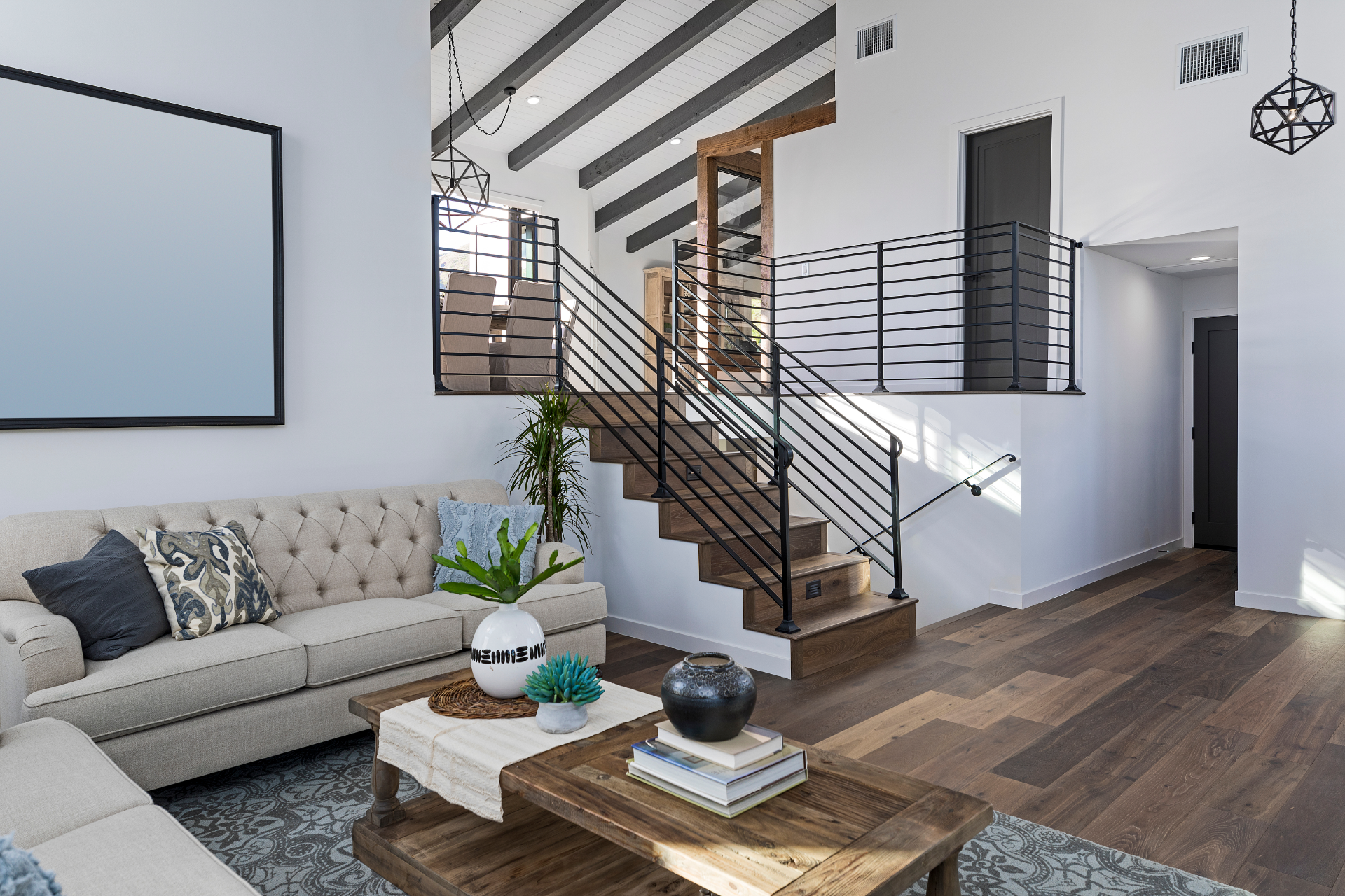 Living room with sofa, staircase, and hardwood floor. Neutral tones, modern design.
