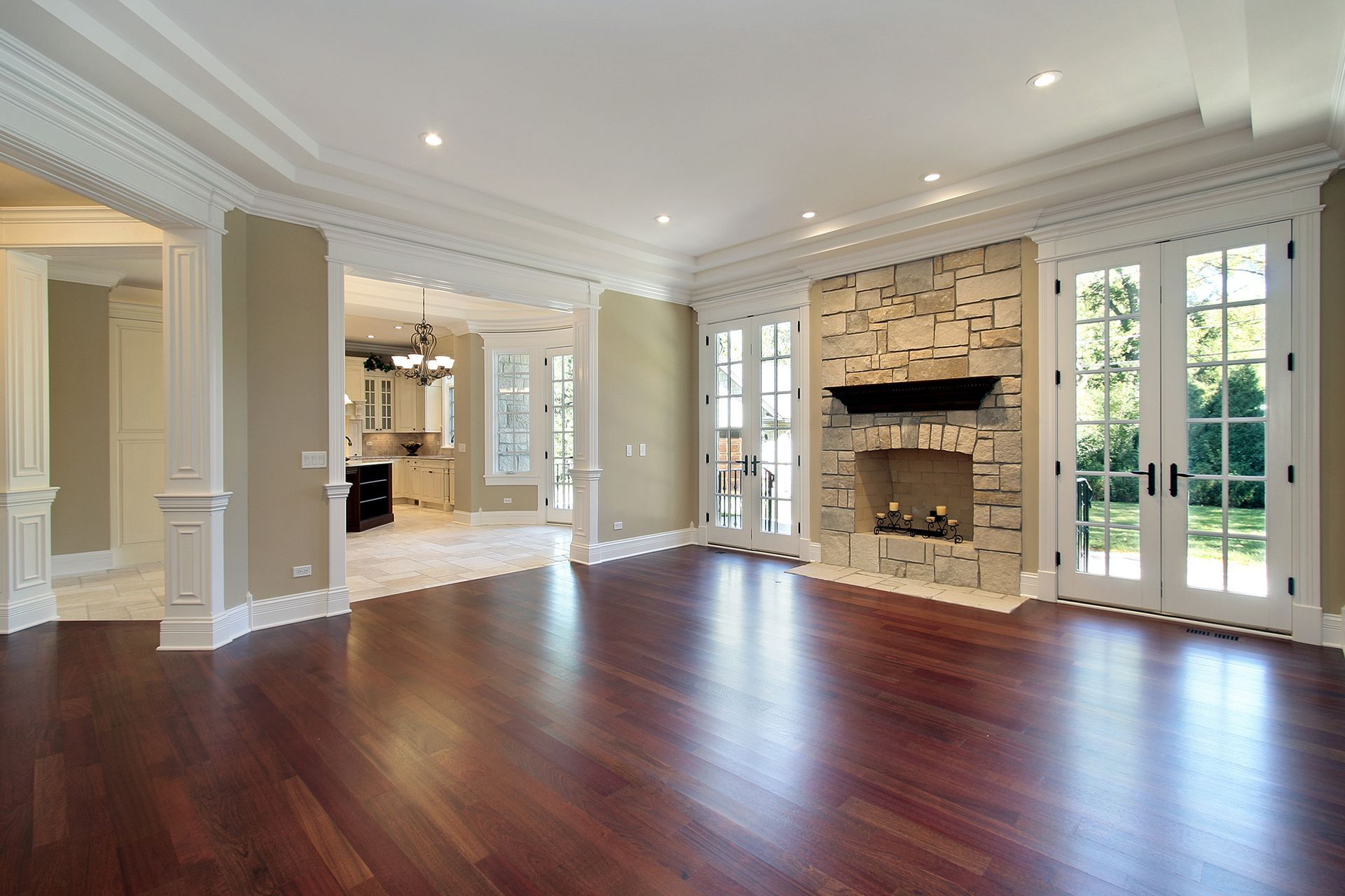 Spacious room with dark hardwood floors, fireplace, and French doors leading to outdoors.
