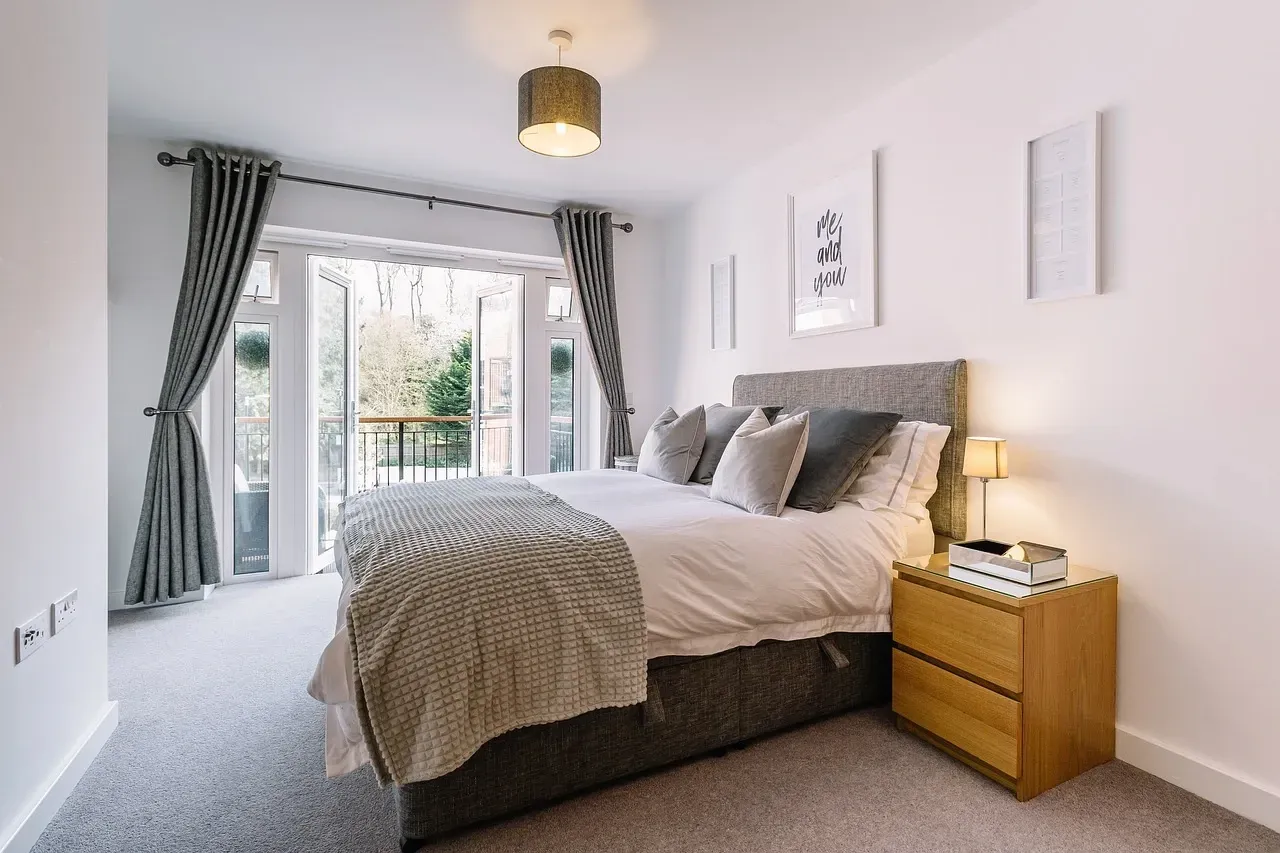 A bedroom with a large bed , nightstand , and sliding glass doors.