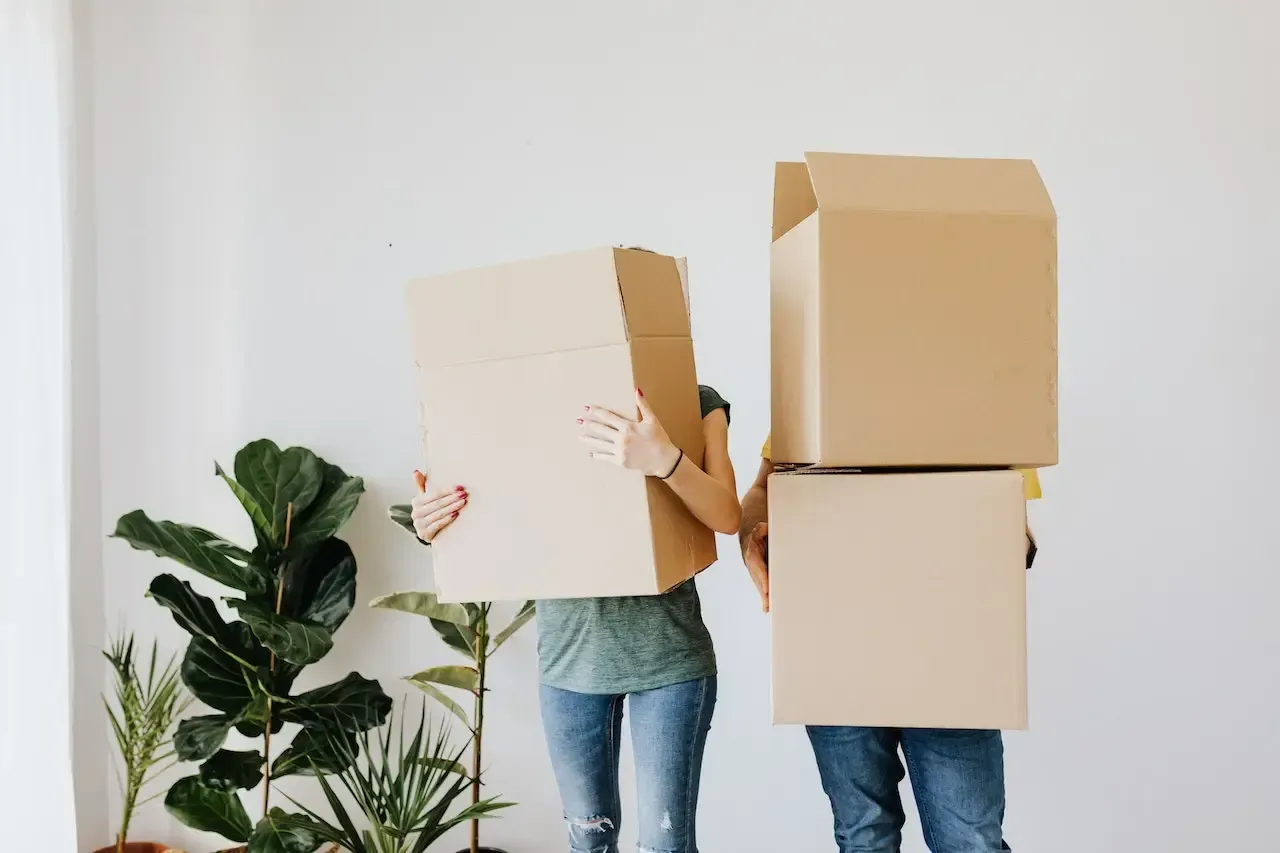 A man and a woman are holding cardboard boxes in front of their faces.