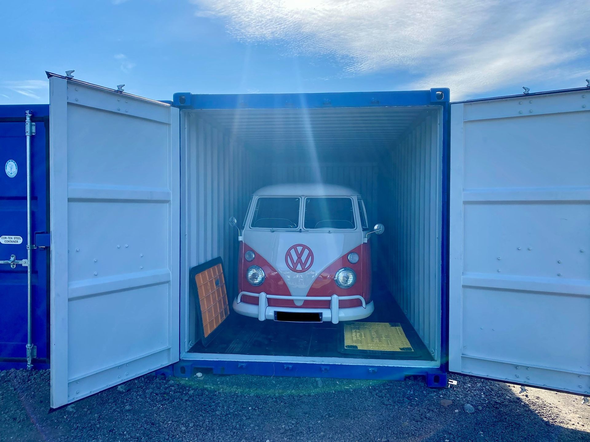 A red and white van is parked inside of a shipping container ANVSJ