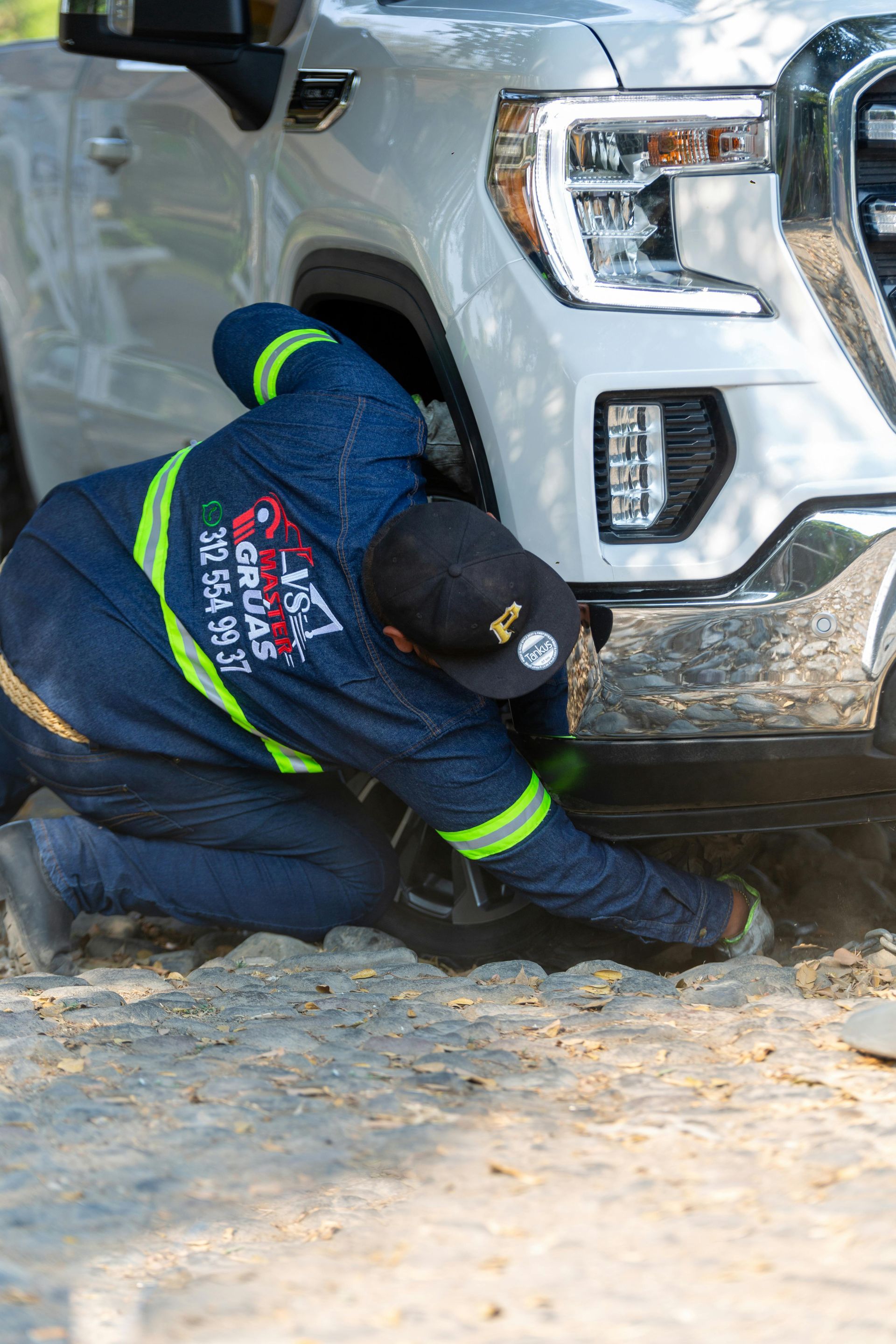 A man is kneeling down next to a white truck.