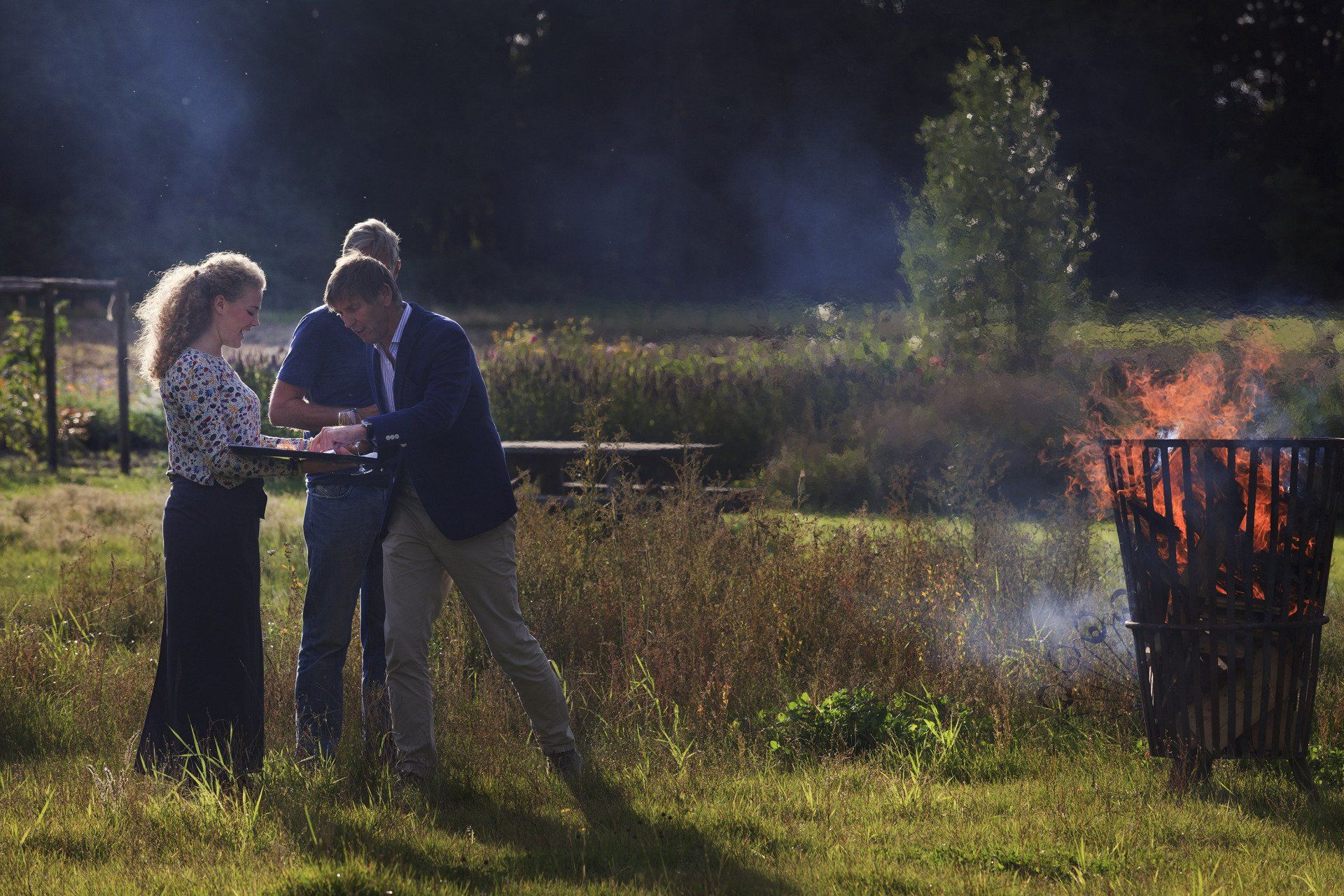 Drie mensen staan ​​buiten bij een vuur 