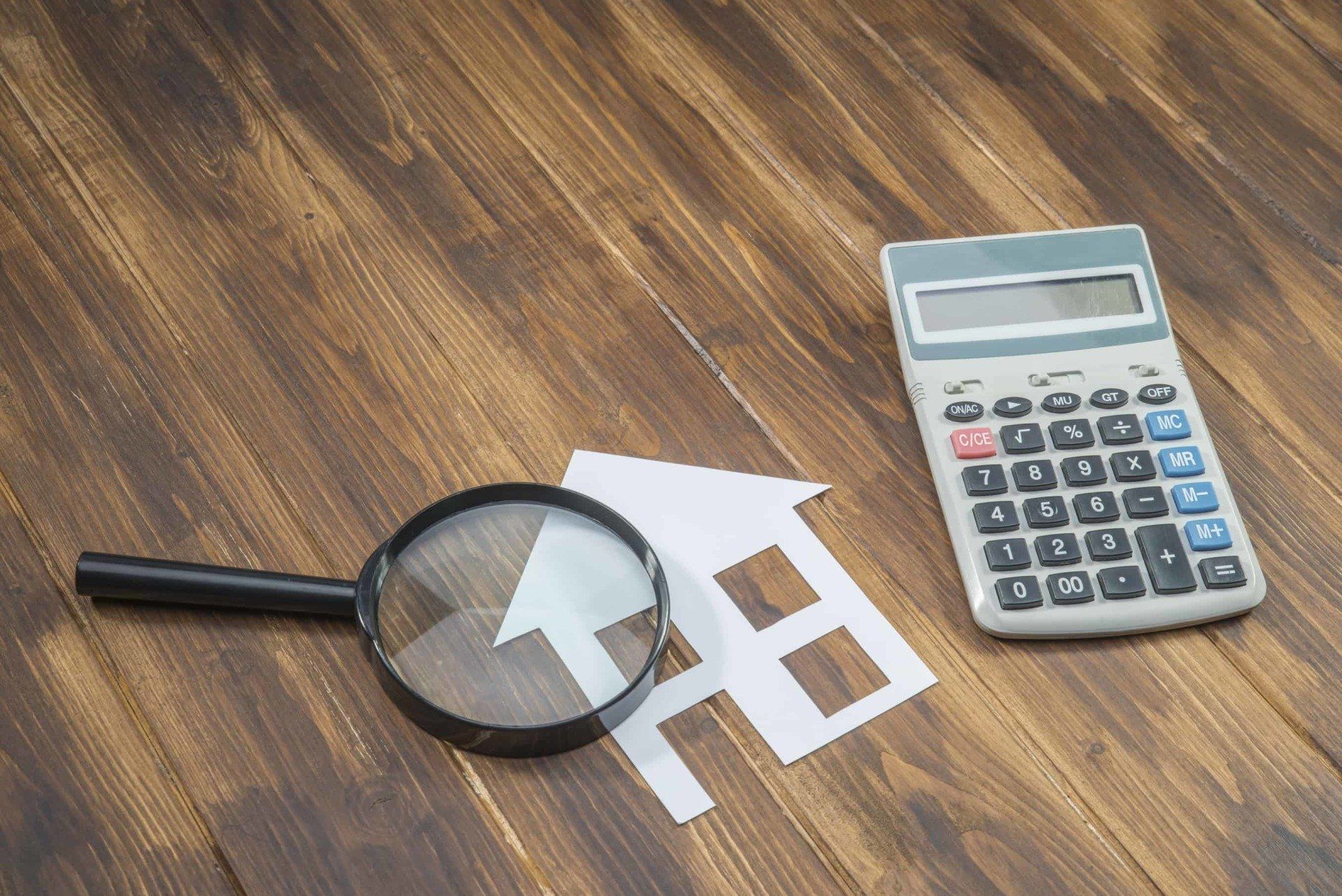 magnify-glass-and-calculator-over-a-paper-house