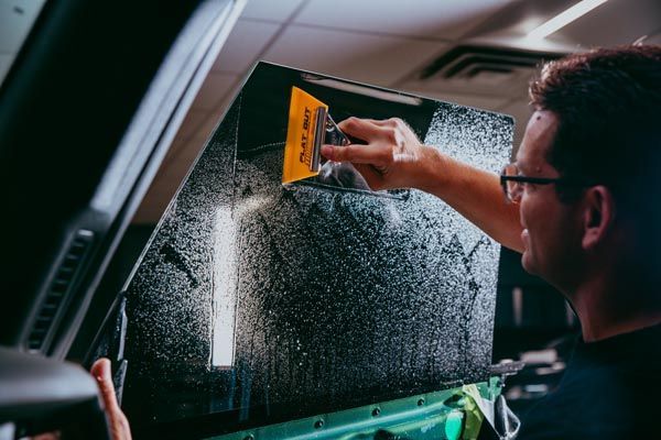 A man in a harley accurate shirt looks at his reflection in a car window
