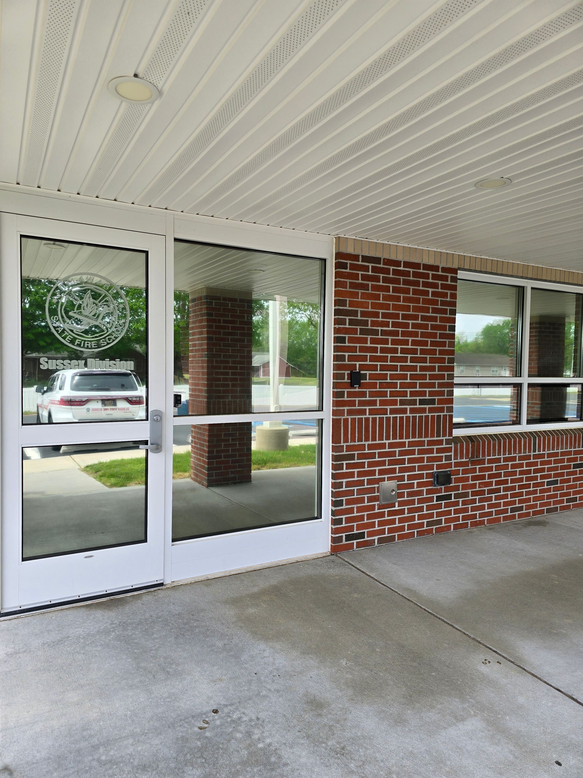 A white car is parked in front of a brick building