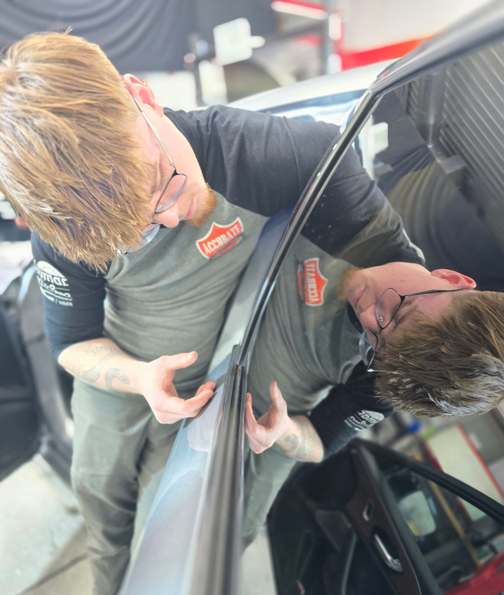 A man in a harley accurate shirt looks at his reflection in a car window