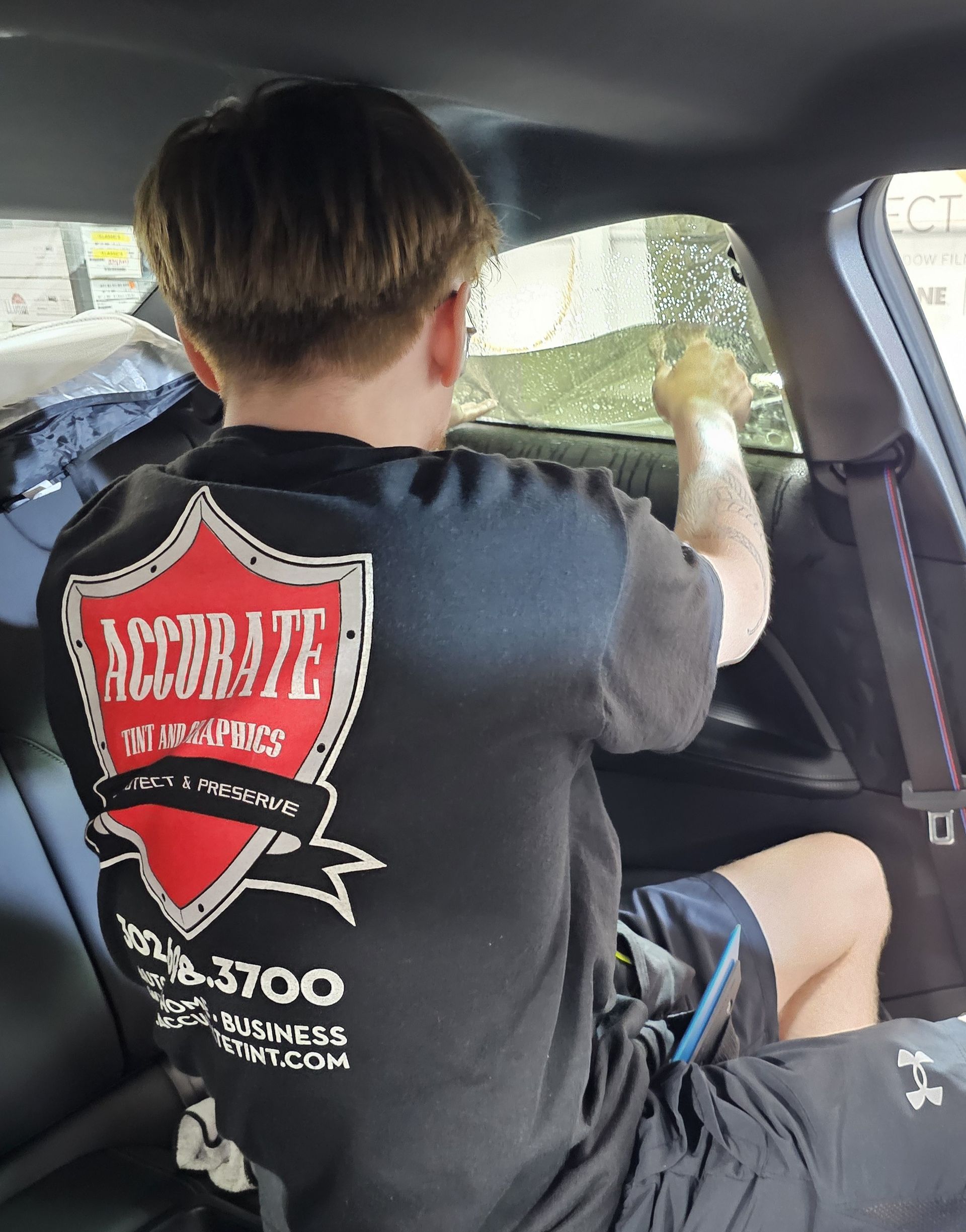 A man is sitting in a car wearing a t-shirt that says accurate