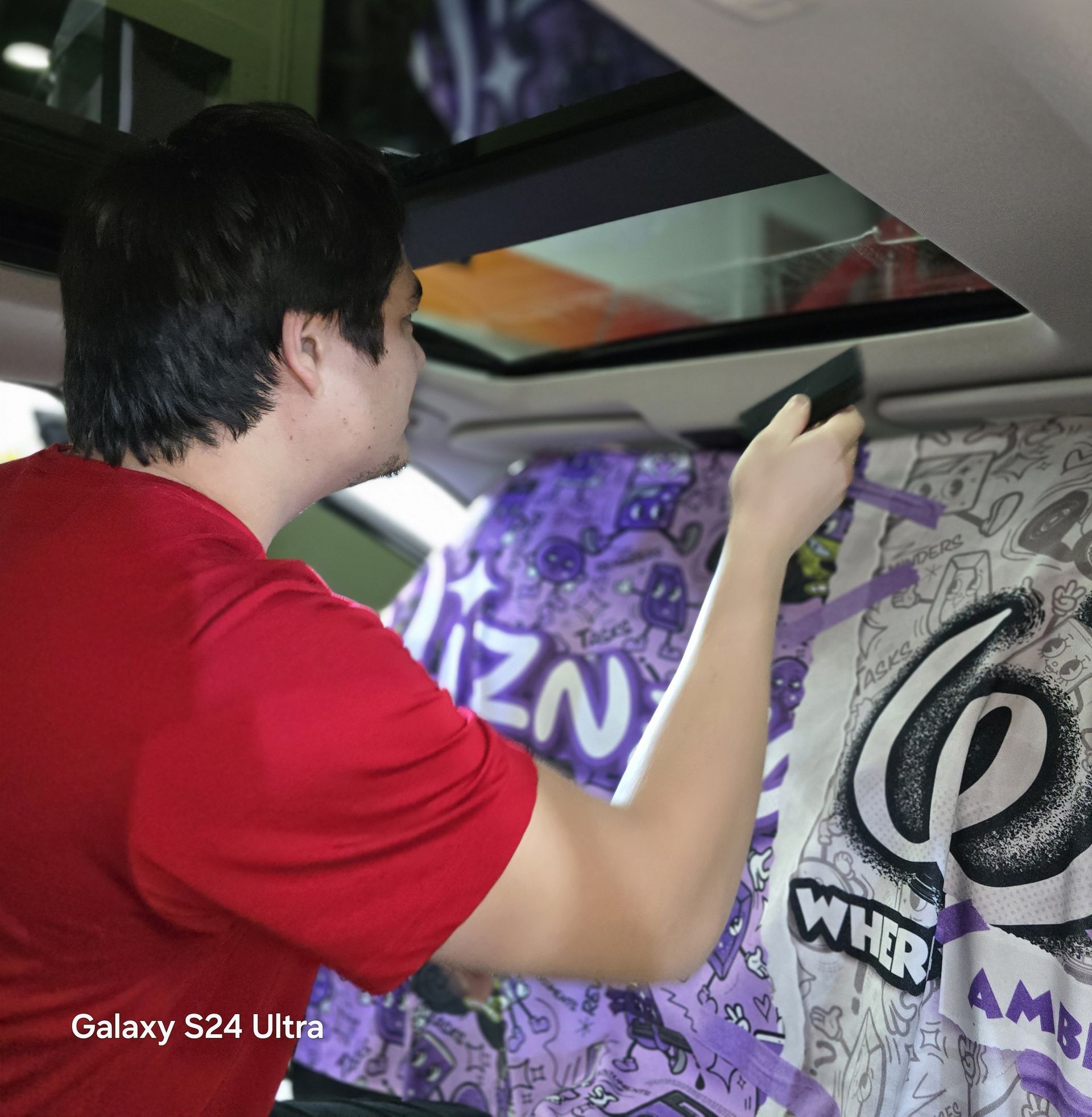 A man in a red shirt is working on a galaxy s24 ultra