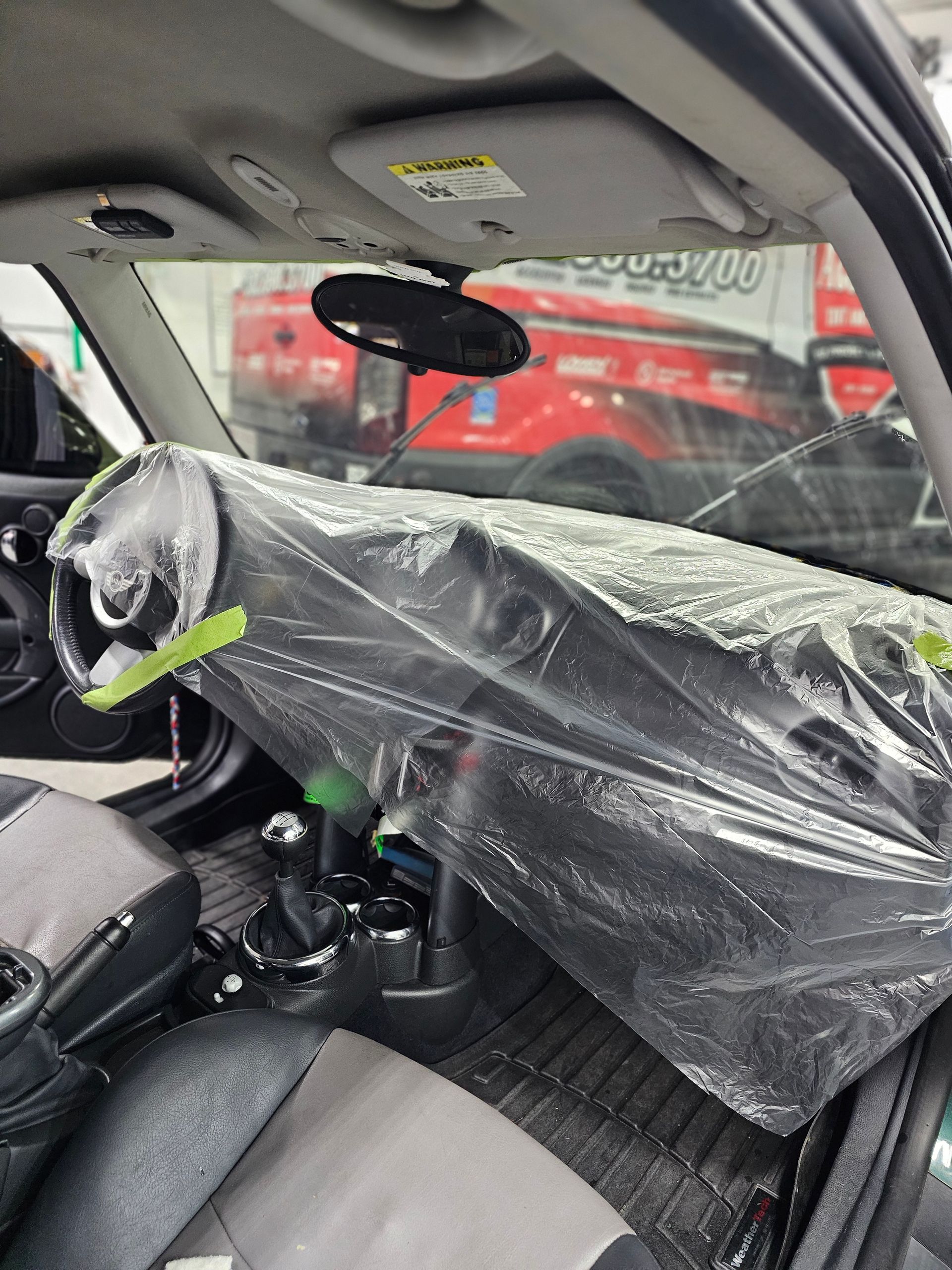 The dashboard of a car is wrapped in plastic.