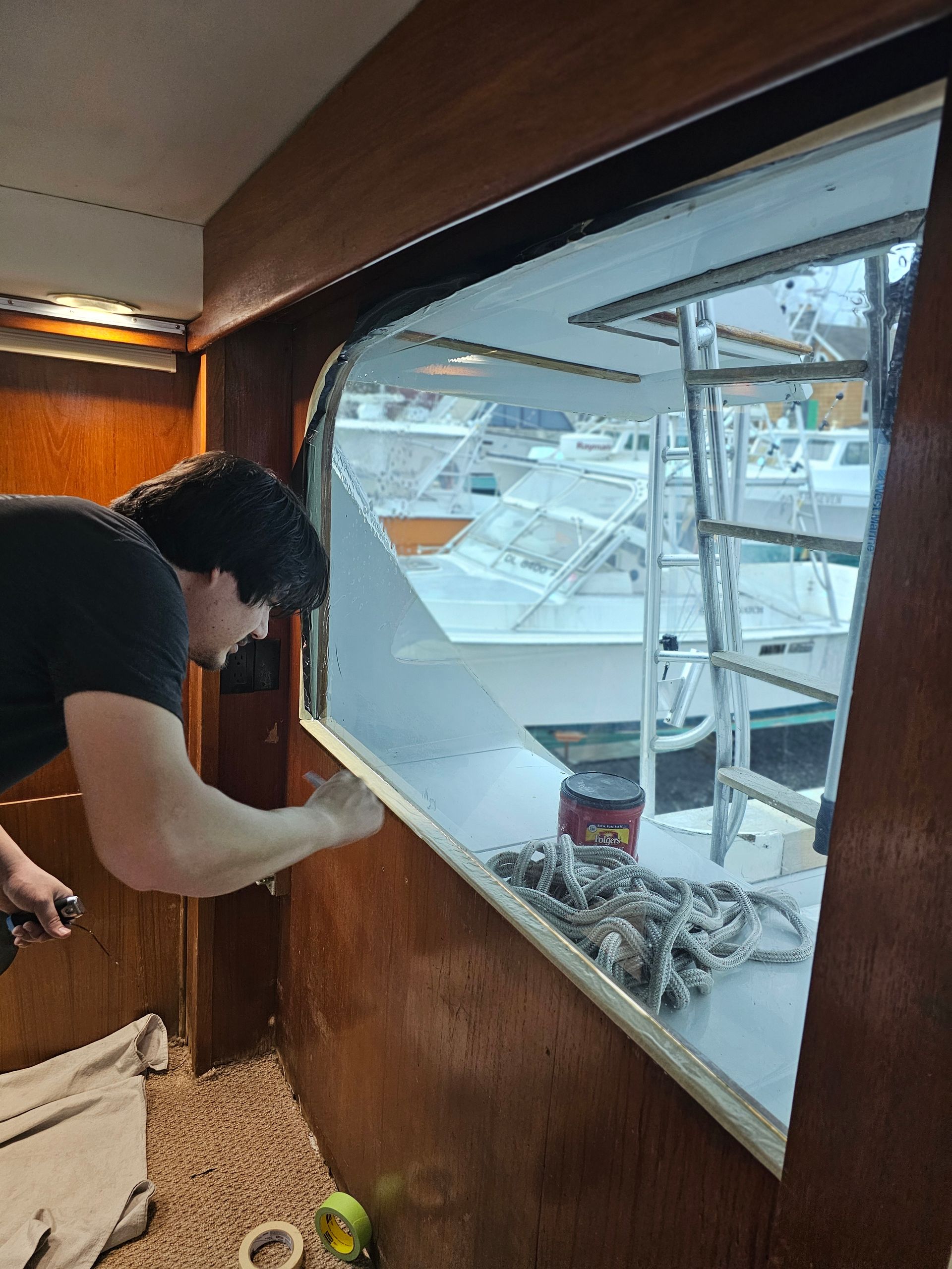 A man is working on a window on a boat.