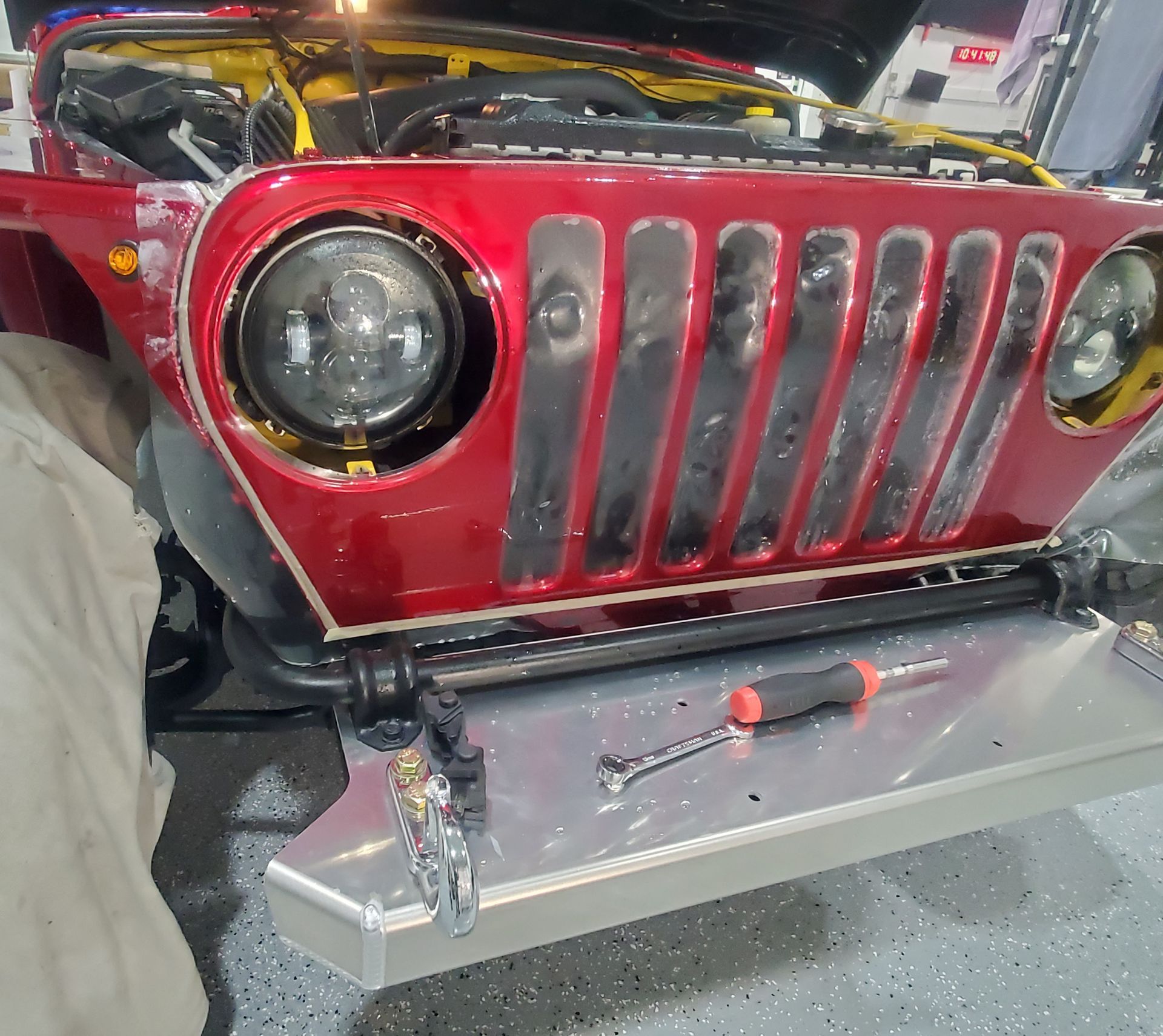 A red jeep is being worked on in a garage