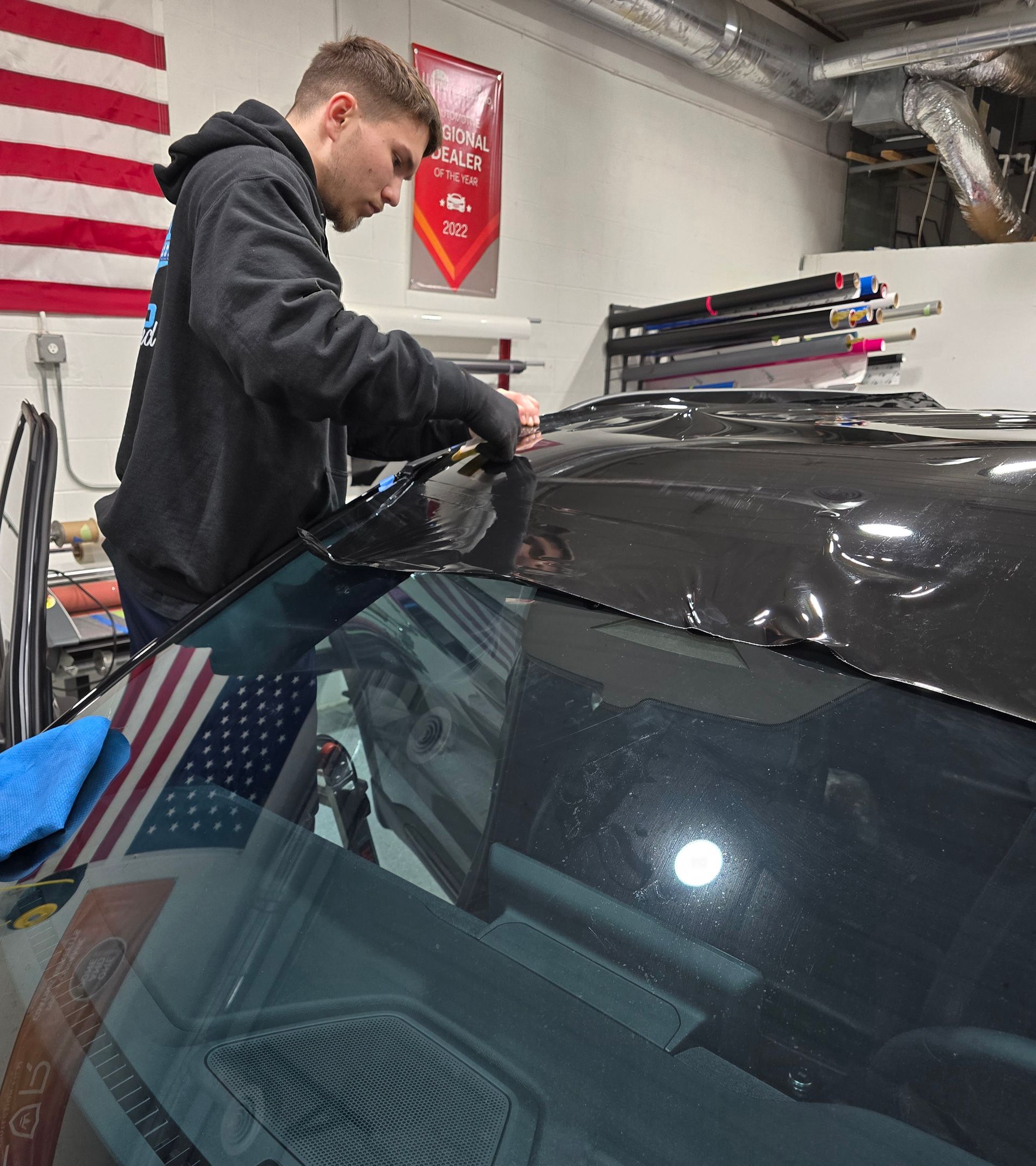 A man is working on the hood of a car in a garage.