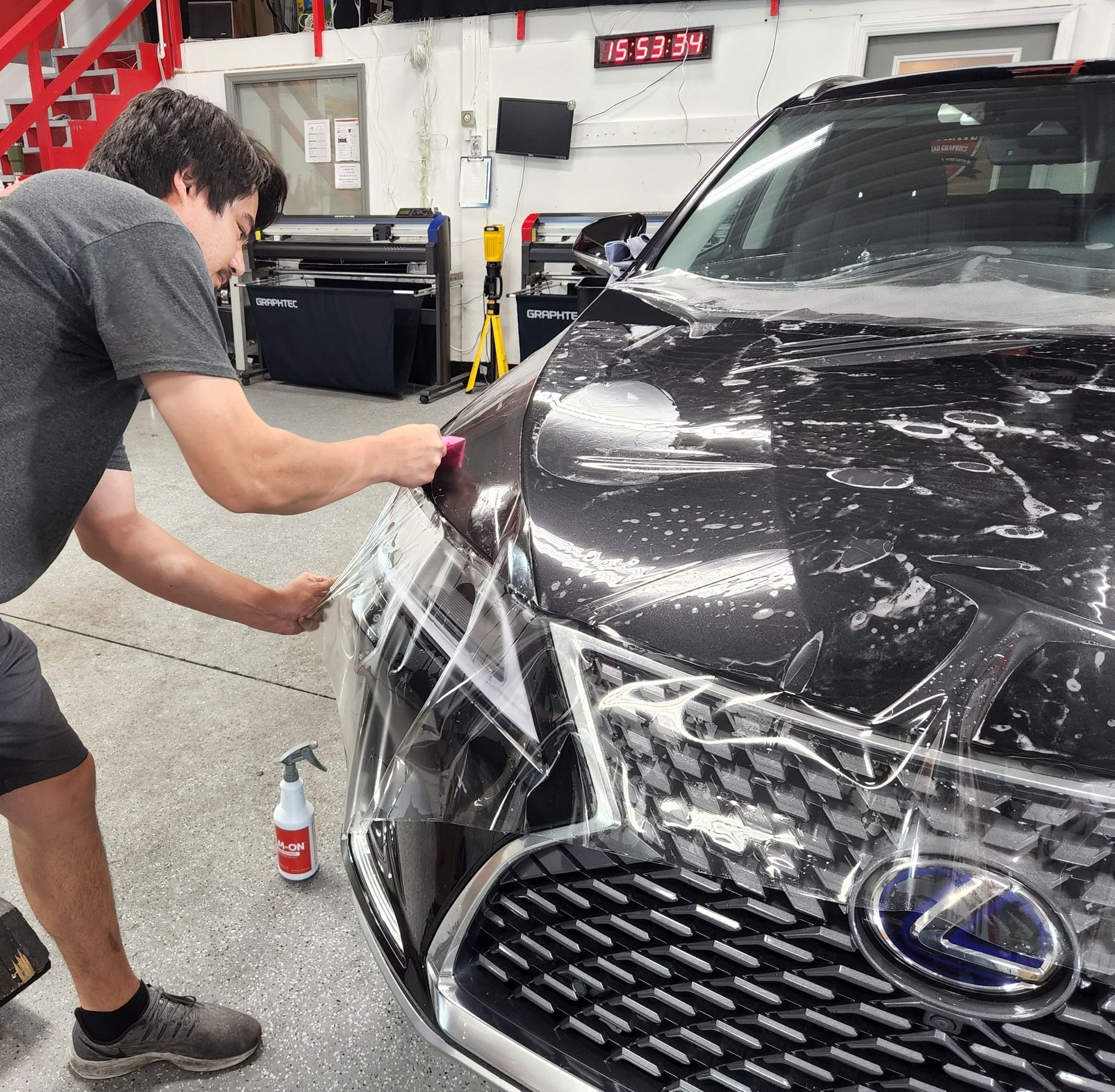 A man is working on a black lexus car