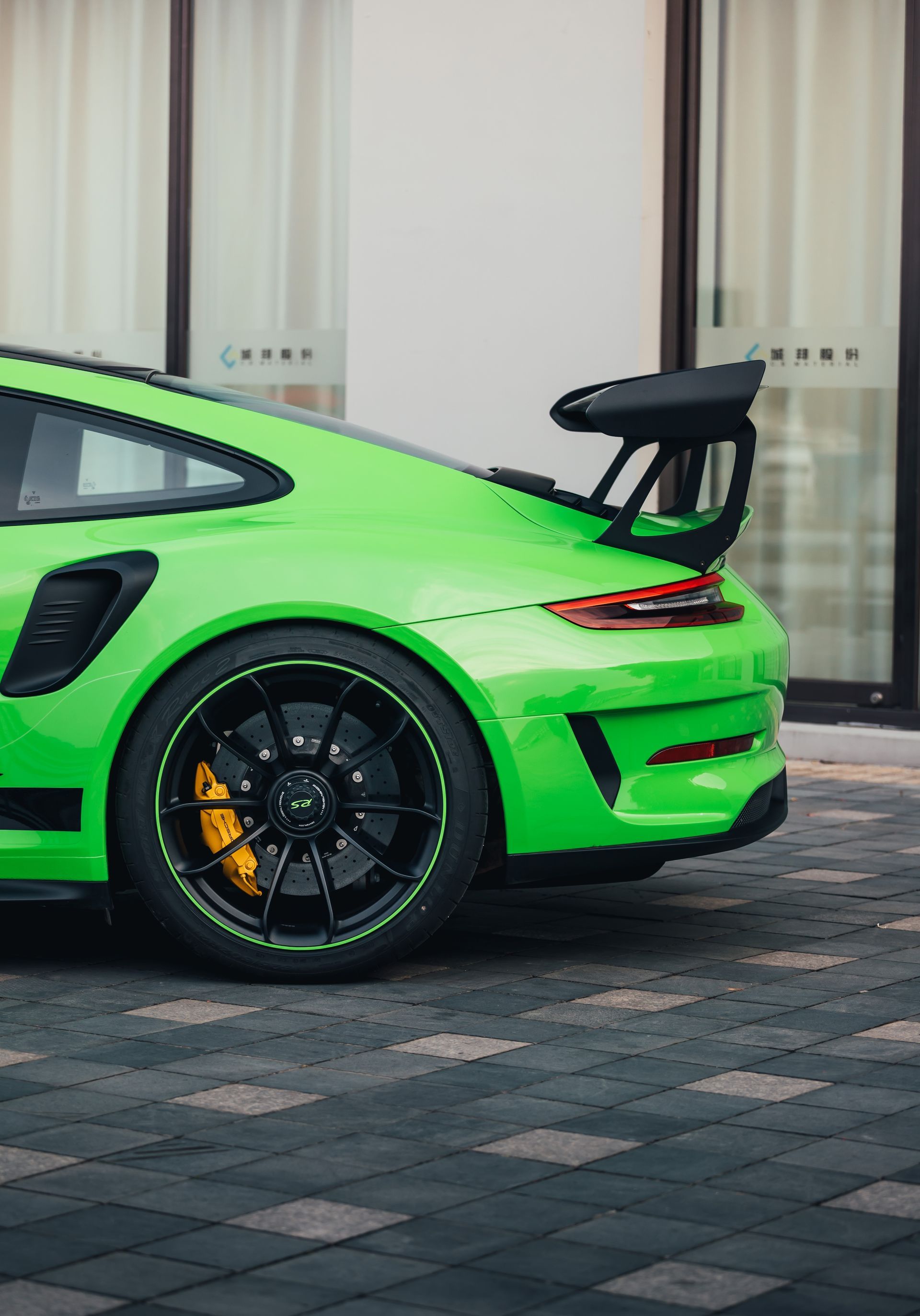 A green sports car is parked in front of a building.