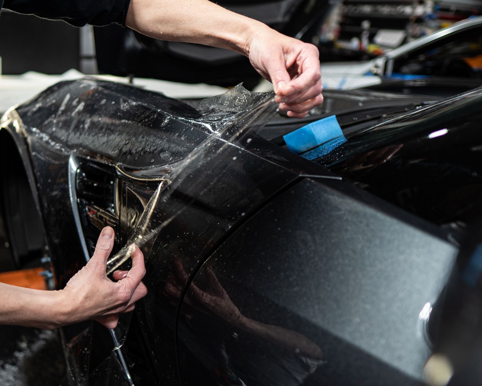 A person is applying a protective film to a car.