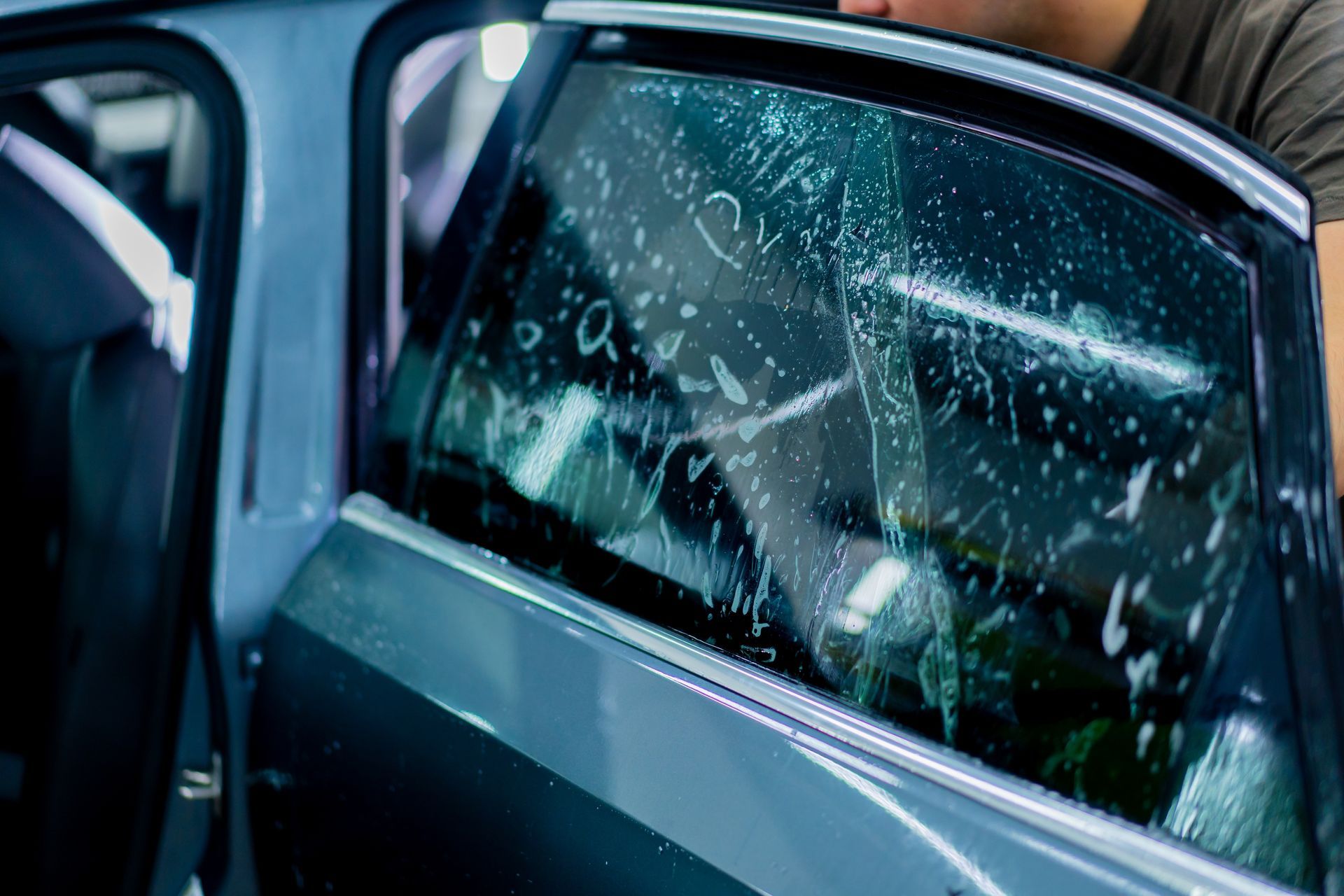 A man is applying window tinting to a car window.