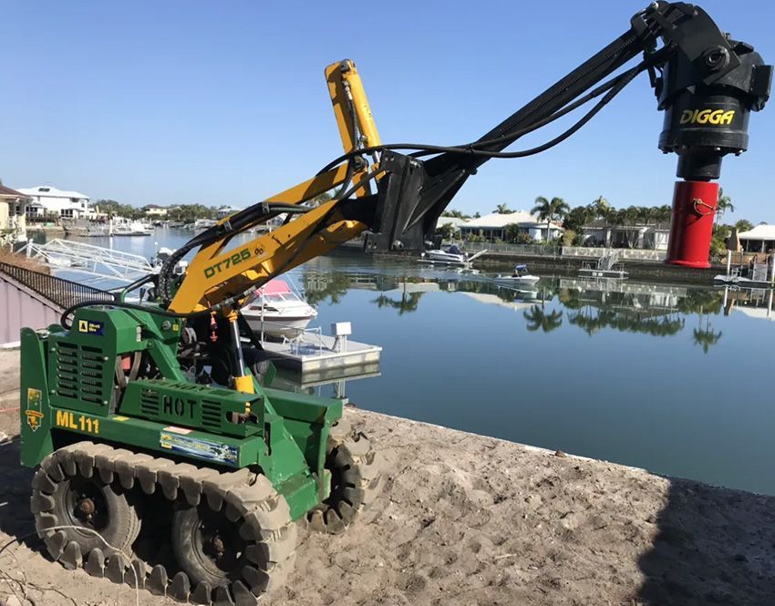 A Green and Yellow Tractor Next to a Body of Water — Hardarc Engineering in Coolum Beach, QLD