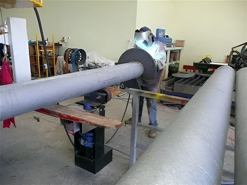 A Man is Welding a Pipe in a Garage — Hardarc Engineering in Coolum Beach, QLD