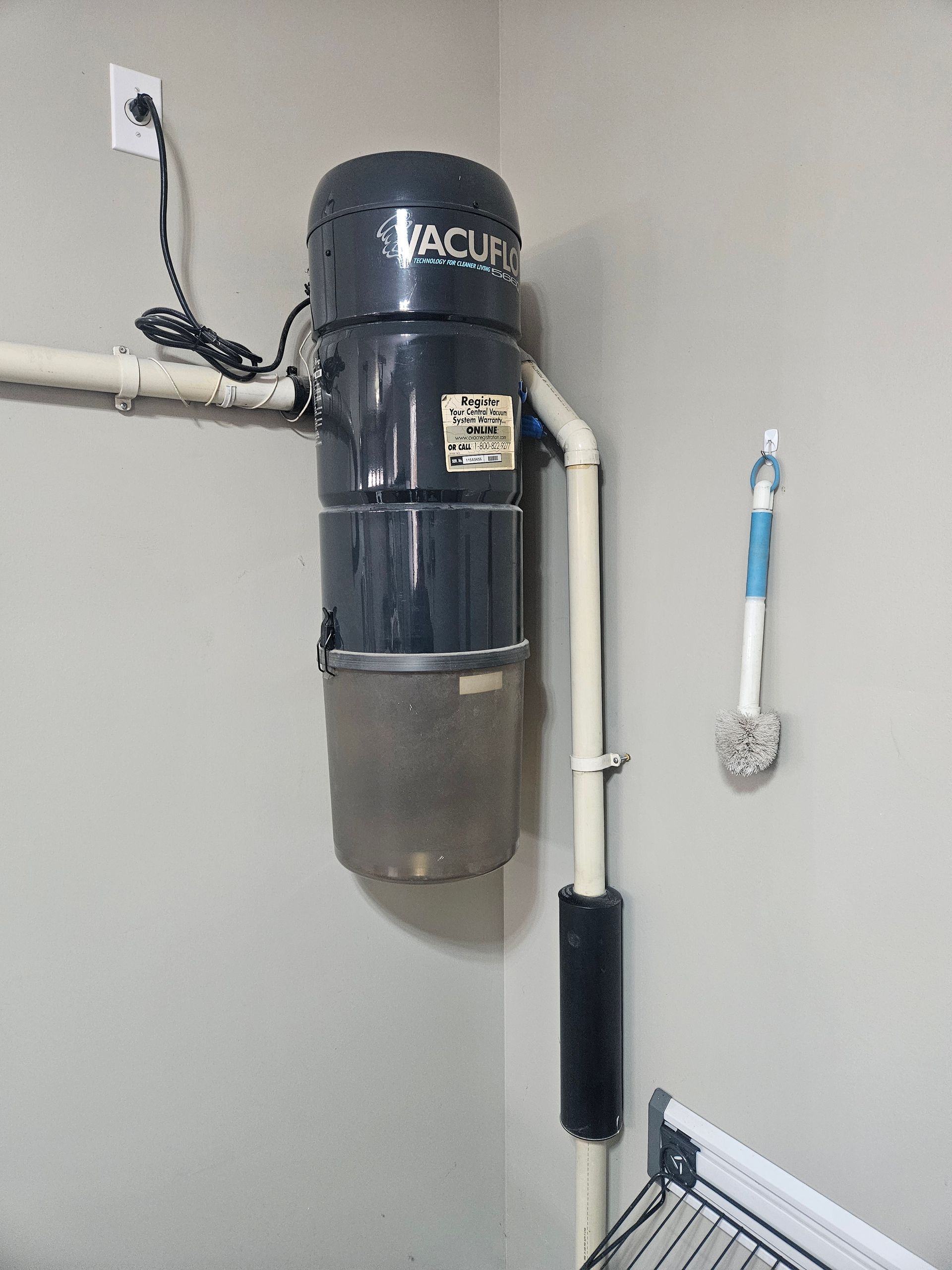 A vacuum cleaner is mounted to the wall in a laundry room.