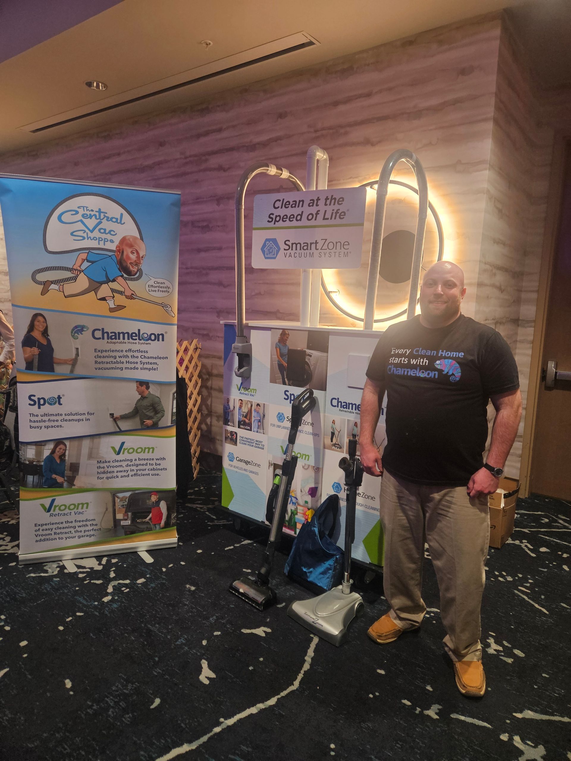 A man is standing in front of a table with a vacuum cleaner on it.