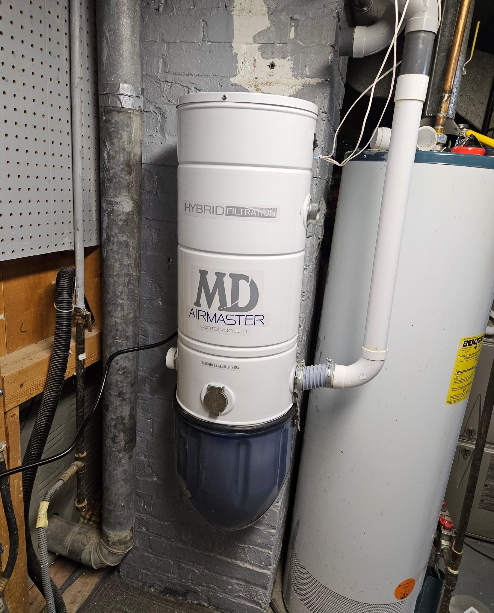 A white md vacuum cleaner is mounted on a wall next to a water heater.