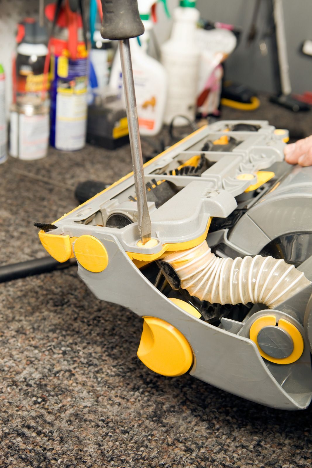 White and black vacuum cleaner on gray tiled floor.