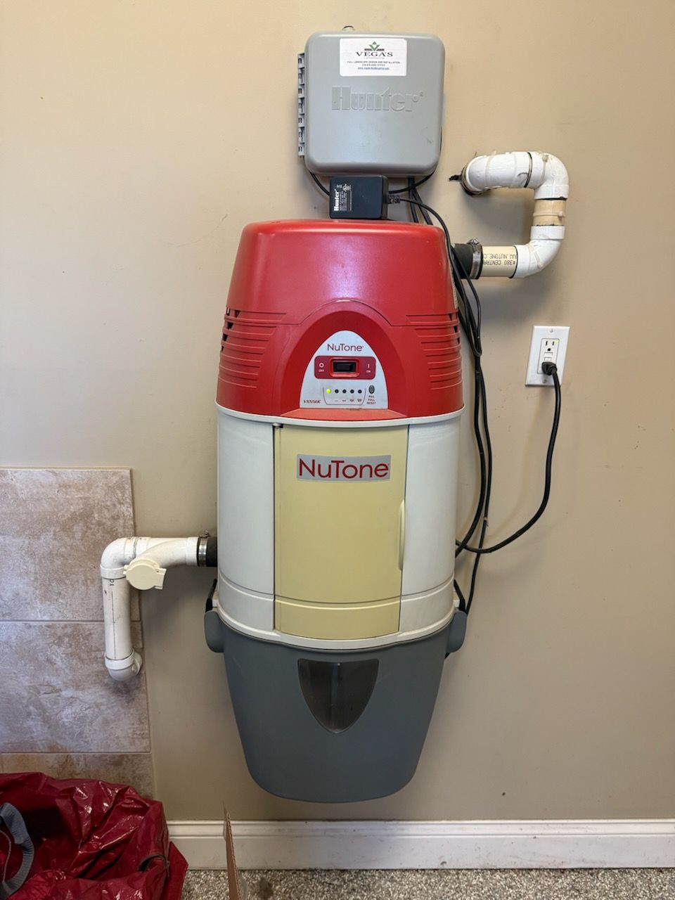 A nutone vacuum cleaner is hanging on a wall.