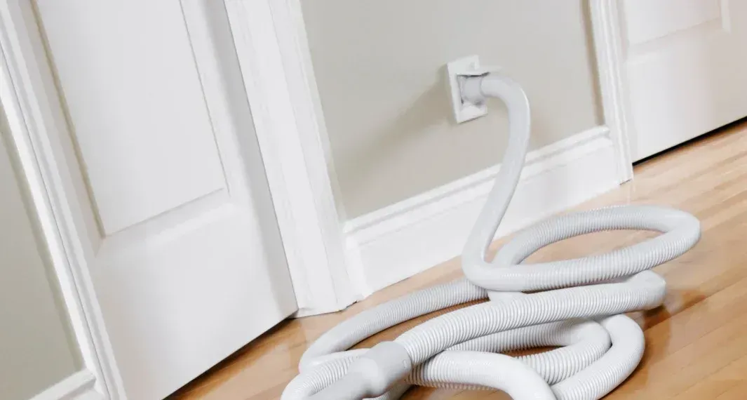 A vacuum hose is laying on the floor next to a door.