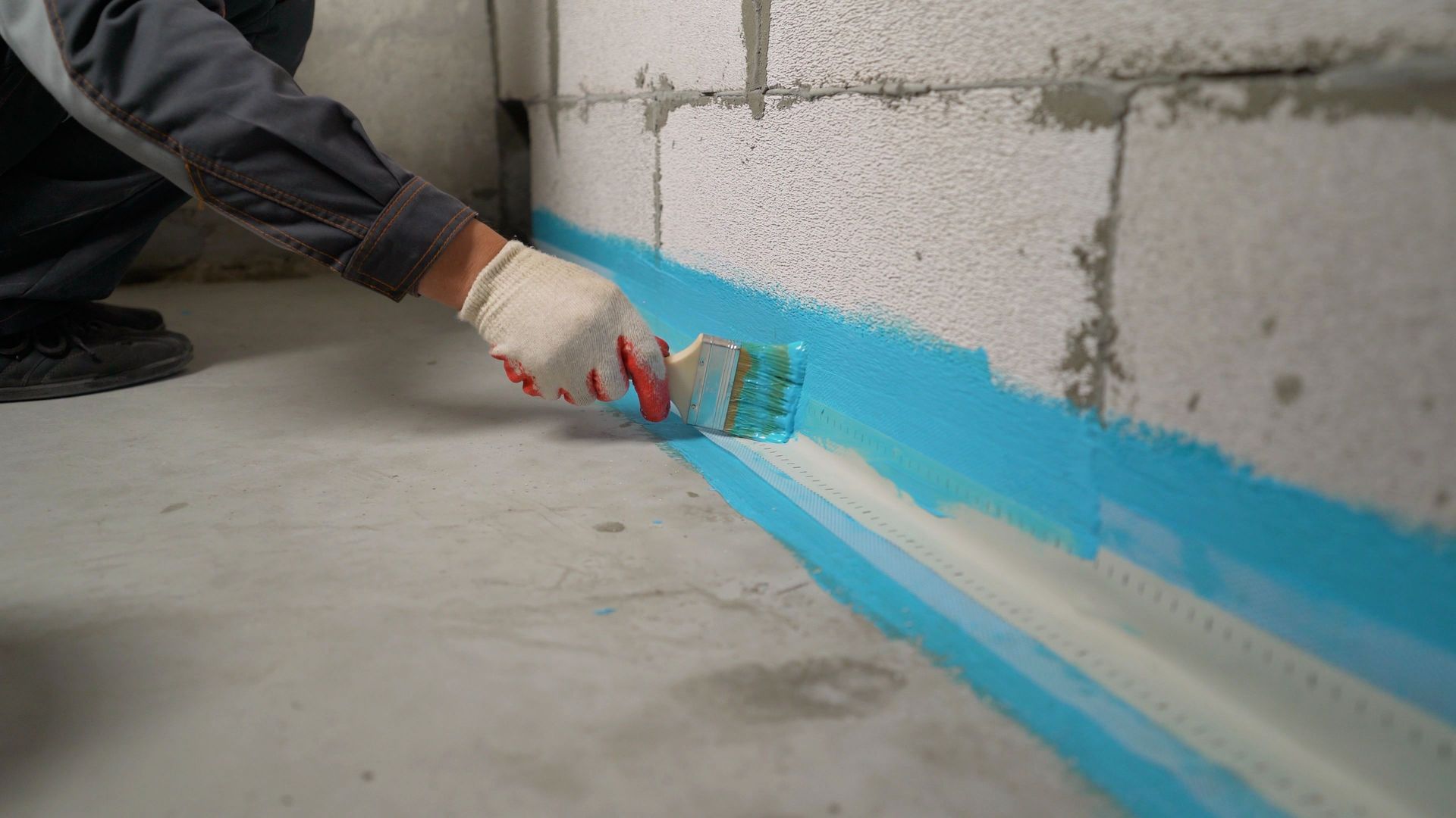 Construction worker applying waterproofing paint on basement wall. Construction worker applying waterproofing paint on basement wall.