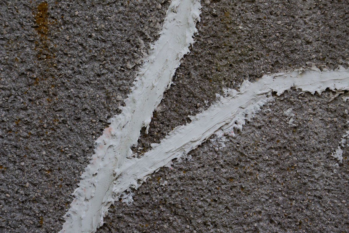 Close-up of gray, textured stone with white mortar in a V-shaped pattern.