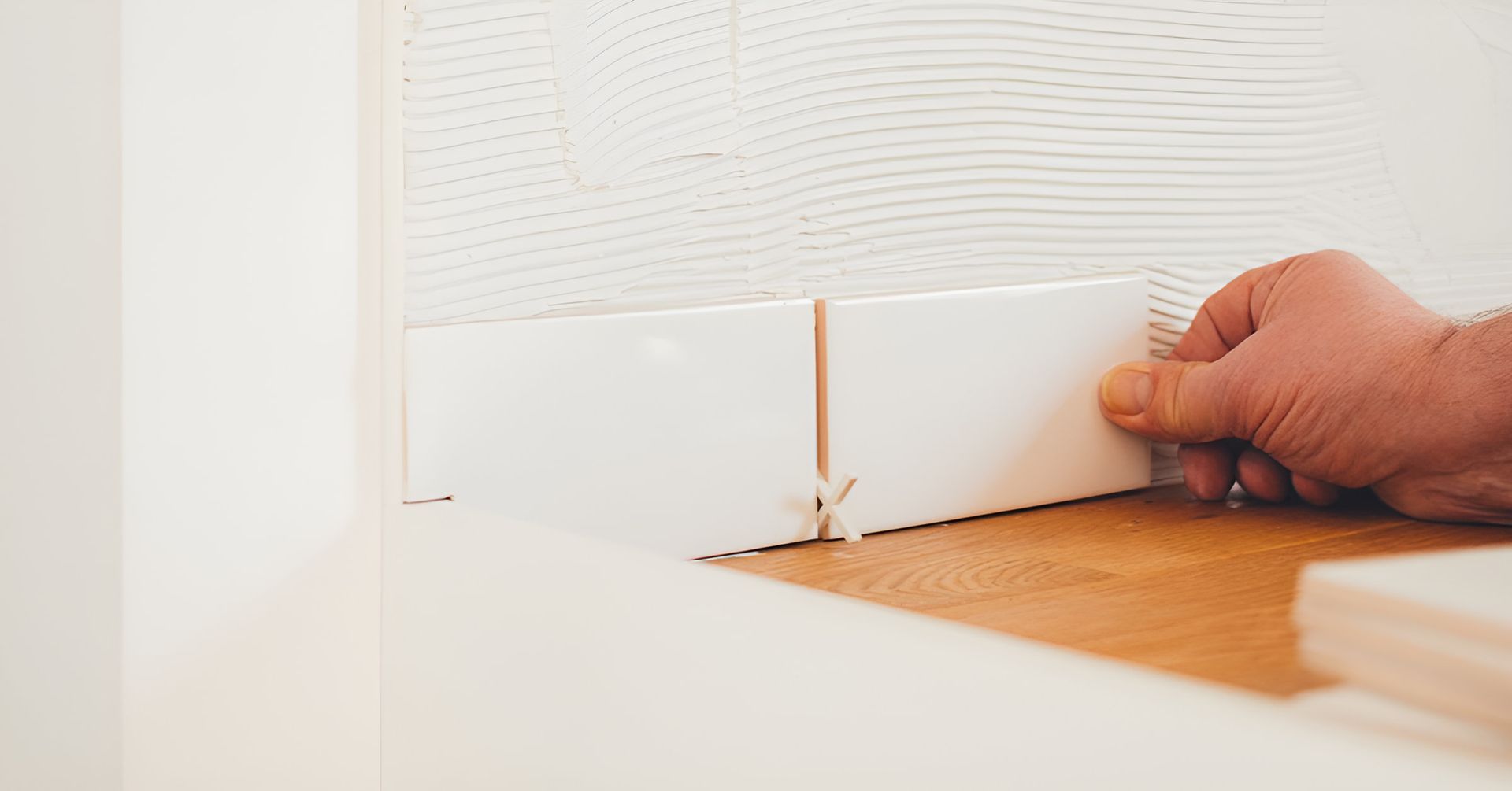 A Person Is Laying Tiles On A Wooden Floor — Mid Coast Tiles Urunga In Urunga, NSW