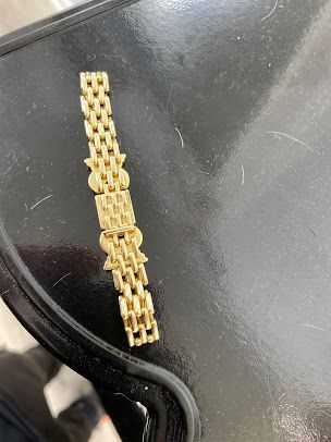 A gold bracelet is sitting on a black table.