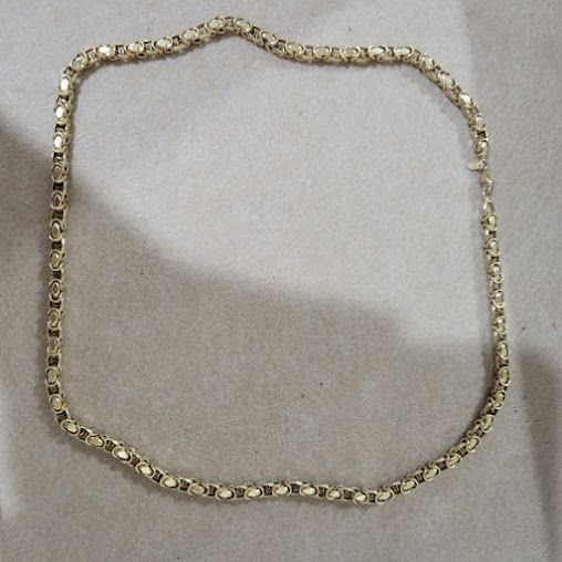 A gold chain is laying on a white surface