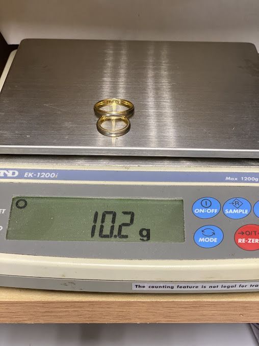 A pair of wedding rings are sitting on top of a digital scale.