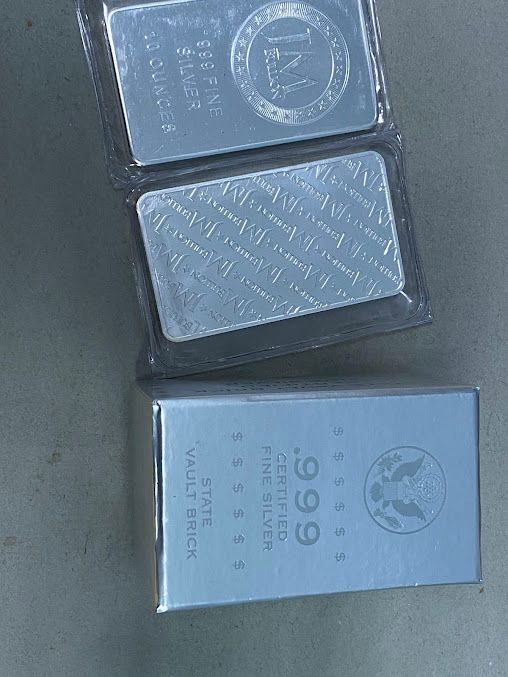 Two bars of silver sitting on top of each other on a table.