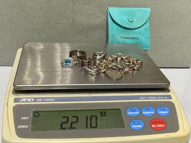 A scale with jewelry on it and a tiffany bag next to it.