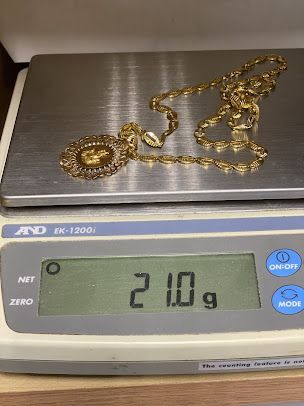A gold necklace is sitting on top of a digital scale.