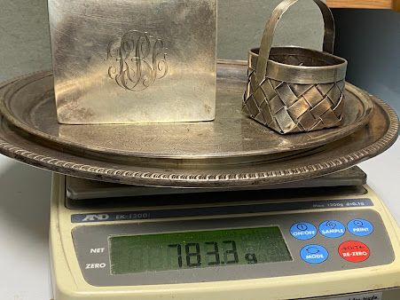 A silver basket is sitting on top of a silver plate on a scale.