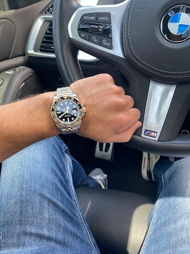 A man is wearing a watch while driving a bmw.