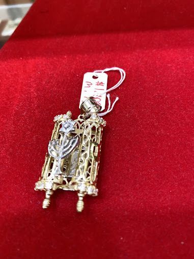 A gold pendant with a tag attached to it is sitting on a red velvet surface.